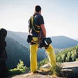 Eine Person steht auf einem großen Felsen neben dem Porträt einer Person 