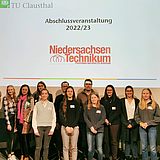 Personen stehen auf der Bühne vor der Projektionsfläche